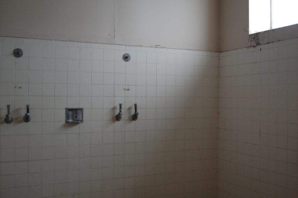 Abandoned shower room with missing fixtures.