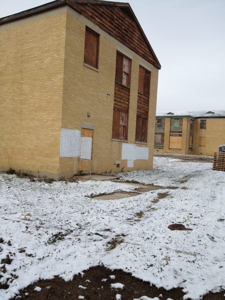 Abandoned Brigham City Indian School with boarded windows and snow covered ground.