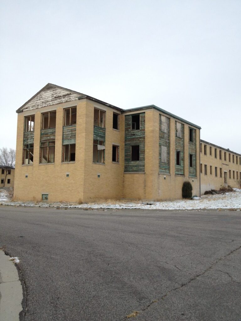 Abandoned yellow-brick building with broken windows and peeling paint at the Brigham City Indian School, taken in December 2012.